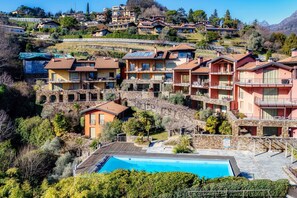 A hillside residential area with multiple two-story buildings, a swimming pool, and a stone retaining wall.