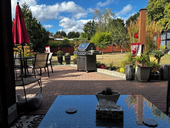 An outdoor patio with a grill, seating area, and potted plants.