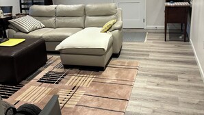 A living room with a beige sofa, a patterned rug, and a small table with a laptop.
