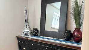 A black dresser with multiple drawers and silver handles, a decorative Eiffel Tower, a vase with green plants, and a mirror with a black frame.