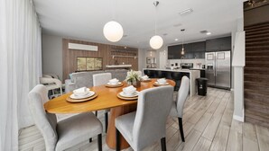 Une cuisine moderne dotée d’un îlot central, d’appareils électroménagers intégrés et de luminaires suspendus.