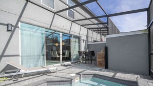 Un espace piscine extérieur moderne doté d’un jacuzzi, de sièges et d’un patio fermé par des baies vitrées.