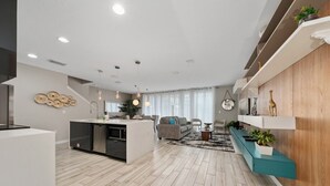 Une cuisine moderne avec un îlot central, un coin repas avec un canapé et des chaises, et un salon avec une table basse.