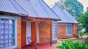 A row of two-story buildings with metal roofs and brick walls, featuring large windows and a small porch area with a chair.