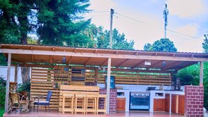 An outdoor patio with a wooden table and chairs, a brick barbecue area, and a built-in oven.