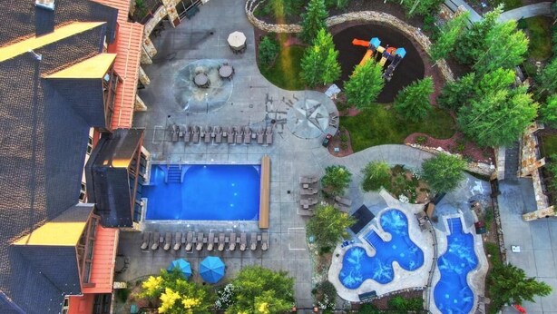 Vue aérienne d’un hôtel doté d’une piscine, d’espaces de détente et de jardins aménagés.