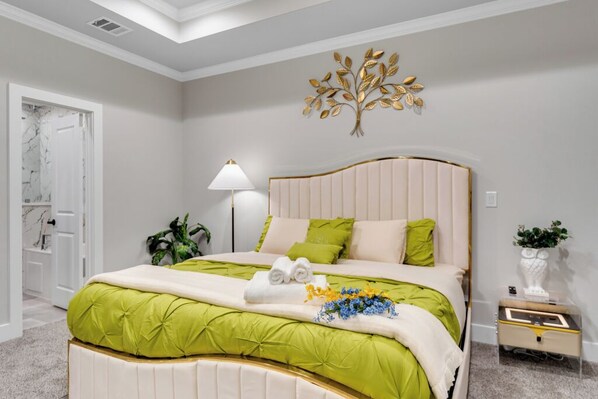 Een slaapkamer met een bed, nachtkastje, lamp en wanddecoratie.