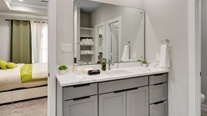 Une salle de bain moderne avec un grand miroir, un plan de toilette blanc et des meubles gris.