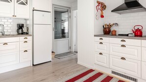 A modern kitchen with white cabinetry, a Bosch range hood, and a red kettle on the countertop. - Sjödrömmen by Interhome (Hudiksvall)