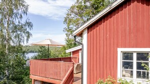A red wooden cabin with a deck overlooking a lake, surrounded by greenery. - Sjödrömmen by Interhome (Hudiksvall)