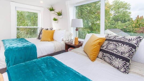 Un dormitorio con dos camas, una ventana y una lámpara.