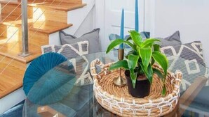 Un interior moderno con una escalera de madera, una mesa de vidrio y una cesta tejida, y un reloj en la pared.