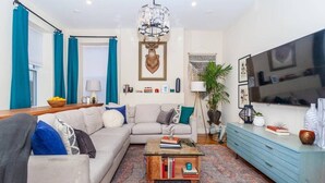 Een woonkamer met een bank, salontafel, televisie en een blauwe kast.