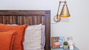 A bed with a wooden headboard, two pillows, a bedside table with a picture frame, a small cactus, and a candle. - Cozy Oasis | Near South End (Boston)