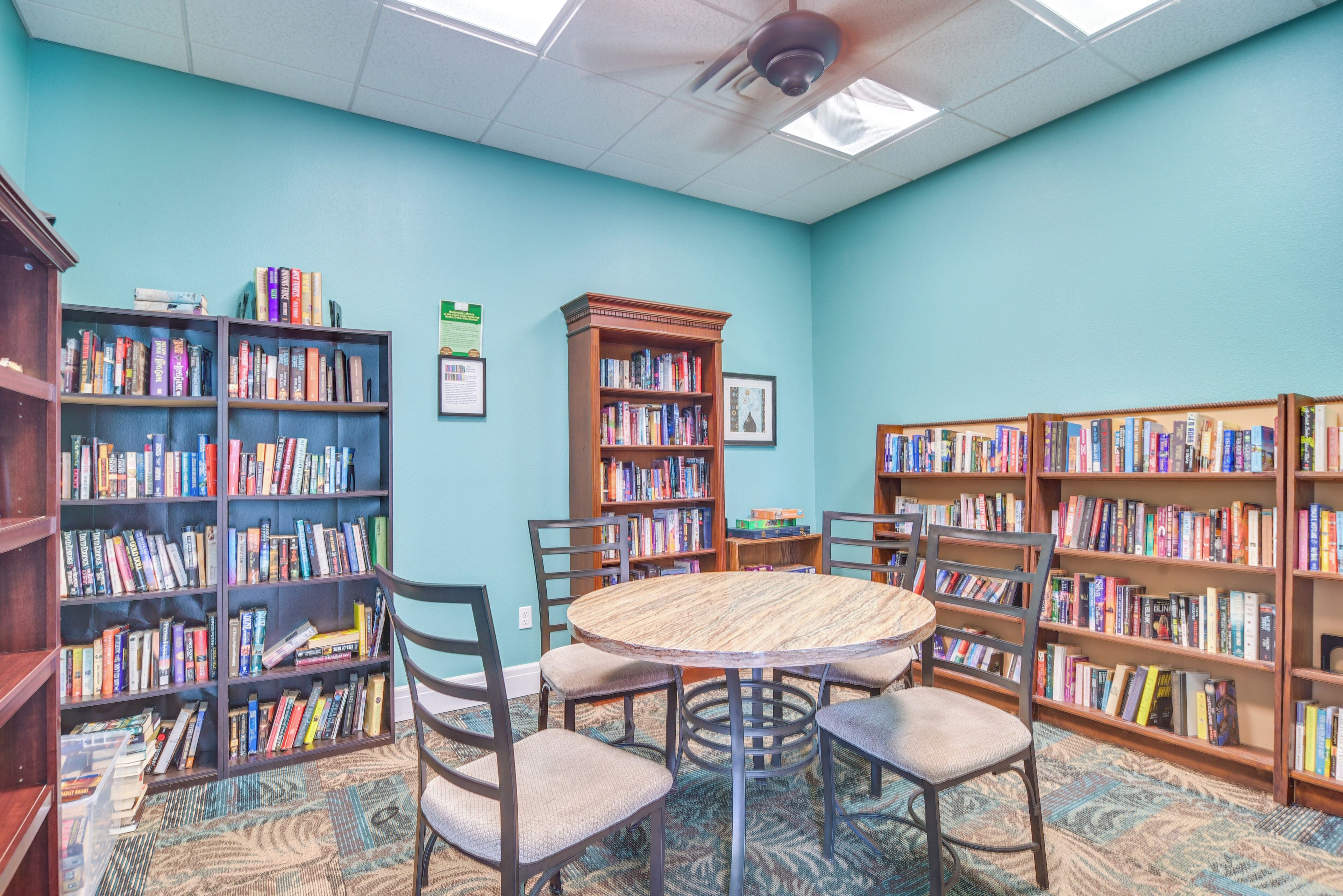 Una biblioteca con una mesa redonda y sillas, rodeada de estanterías llenas de libros.