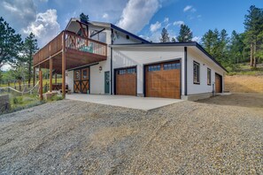 A two-story house with a wooden deck, a garage, and a gravel driveway. - Pristine Cabin, Breathtaking Views in Aspen Grove (Black Hawk)