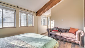 A room with a bed, a leather sofa, and large windows. - Pristine Cabin w/ Stables in Black Hawk by Casinos (Black Hawk)