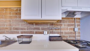 A kitchen with a brick wall, white cabinets, a stainless steel sink, and a stove. - 5 Mi to Casino & Lake: Home on Escondido Ranch! (Escondido)