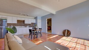 A modern kitchen with white cabinets, a brick backsplash, and a dining area with a table and chairs. - 5 Mi to Casino & Lake: Home on Escondido Ranch! (Escondido)