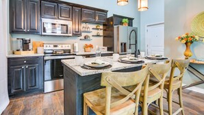 A modern kitchen with dark cabinets, stainless steel appliances, and a central island with seating.