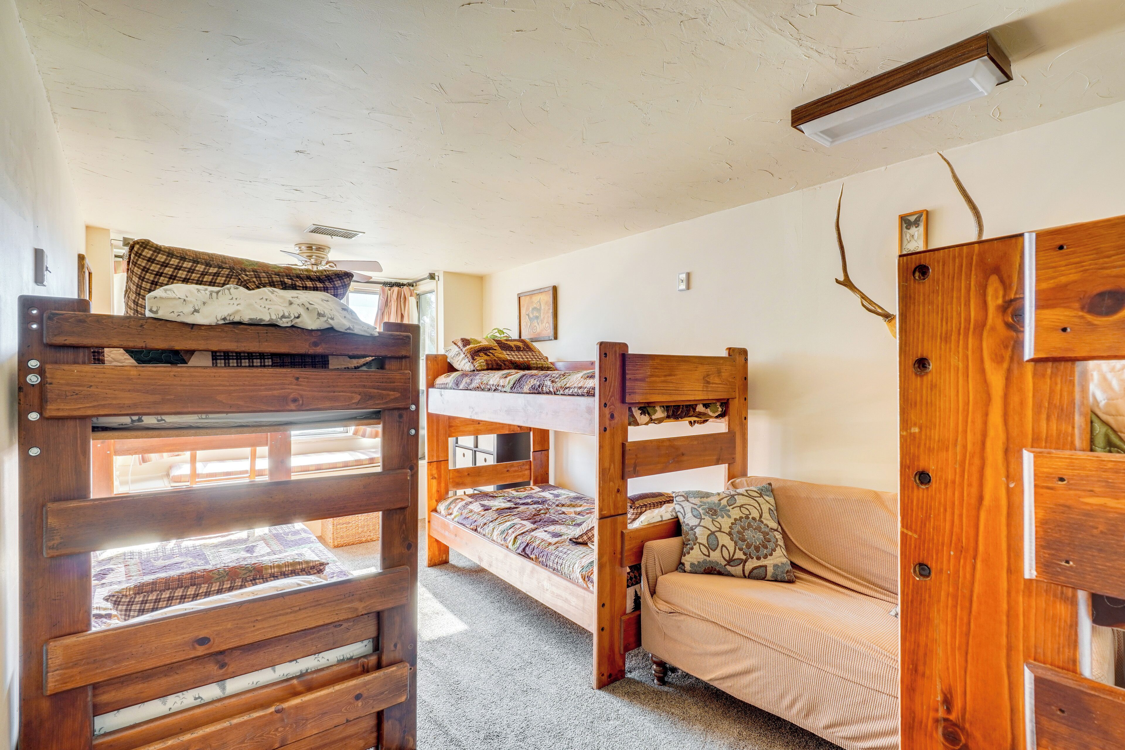 Ein Stockbett mit Holzbettrahmen, ein Sofa und eine Deckenleuchte.