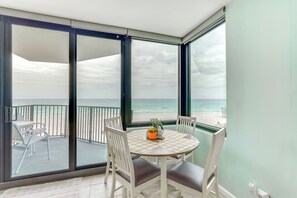 A balcony with a table and chairs, a view of the ocean, and a potted plant on the table. - Gulf-View Balcony: Beachfront Condo in PCB! (Panama City Beach)