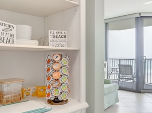 Cozinha com um aviso indicando 'Cozinha Fechada, Estou na Praia', uma máquina de café e vista para a varanda.