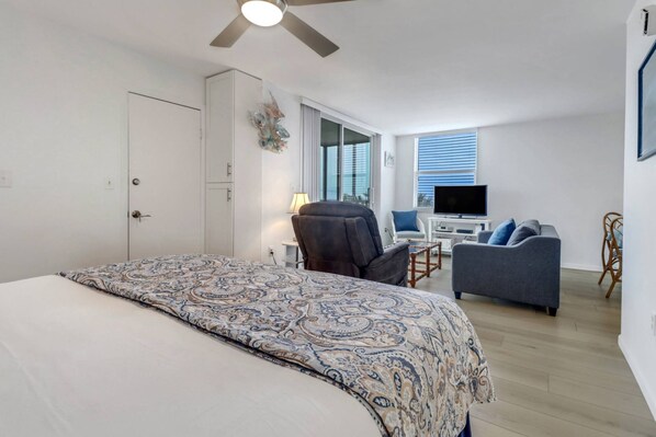 A bedroom with a bed, a desk, a chair, and a sofa.