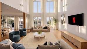 A spacious living room with a large TV, comfortable seating, and a view through the windows. - Mount Martha Manor Indoor Pool & Ocean Views (Mount Martha)