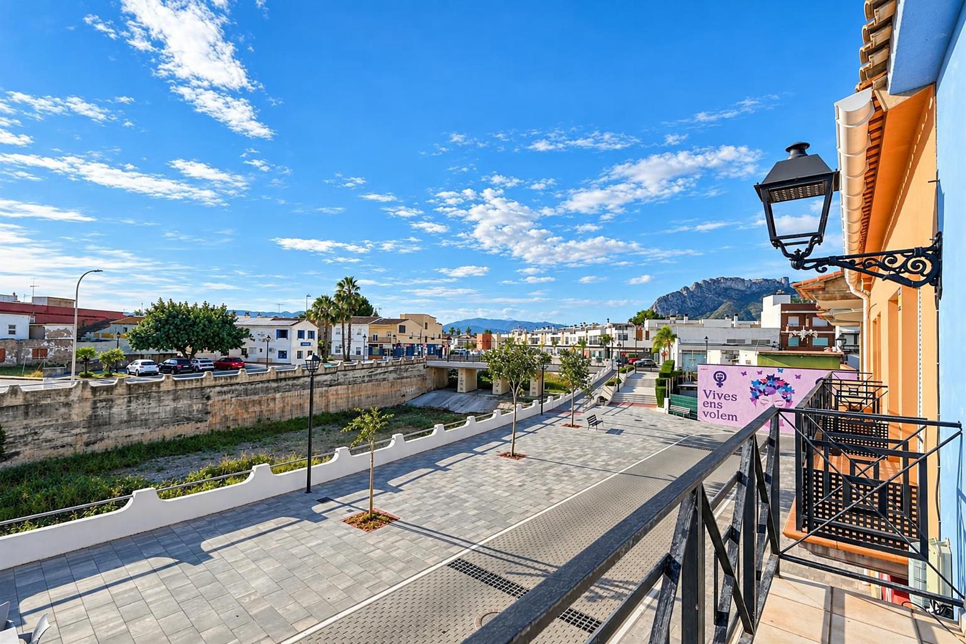 A balcony with a view of a city street, a street lamp, and a mountain in the background.