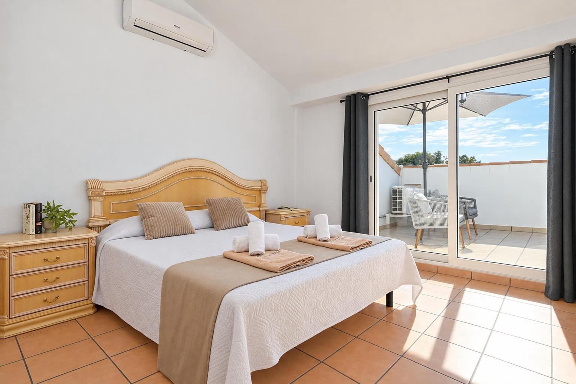 A hotel room with a bed, bedside tables, a window, and a view of the outdoors.