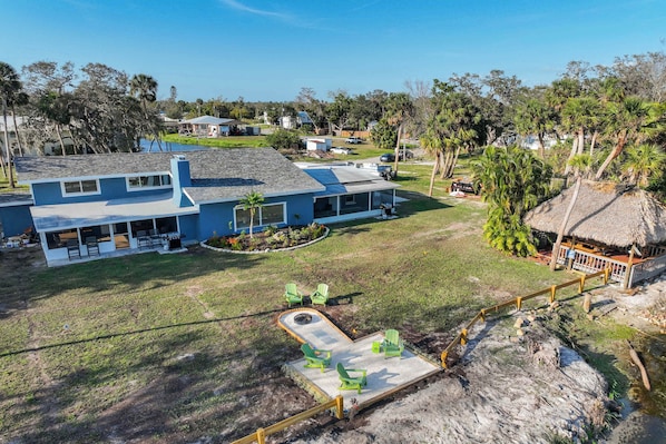 Una casa grande con un porche cubierto, una piscina y una estructura de techo de paja.