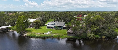 A lakeside property with a house, dock, and surrounding greenery.