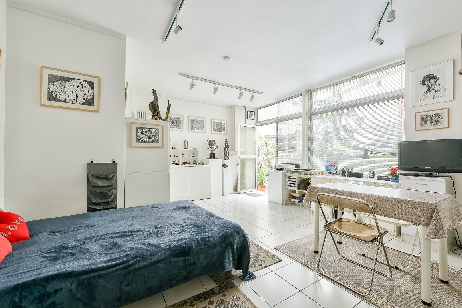 Een moderne slaapkamer met een bed, bureau en televisie.