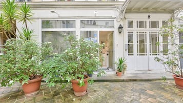A building with a white facade, a door labeled 'B', and potted plants in the foreground.