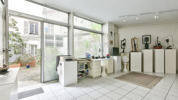 A modern office space with a large window, white desk, and various office supplies.