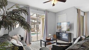 A living room with a sofa, television, and a ceiling fan. - Spacious 4BR Townhome with Pool at Storey Lake (Kissimmee)