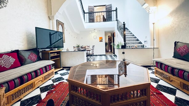 A spacious living room with a high ceiling, a central coffee table, a television, and a staircase leading to an upper level. - TYPICAL RIAD HOUSE MARRAKECH G7 - N51 (Marrakech)