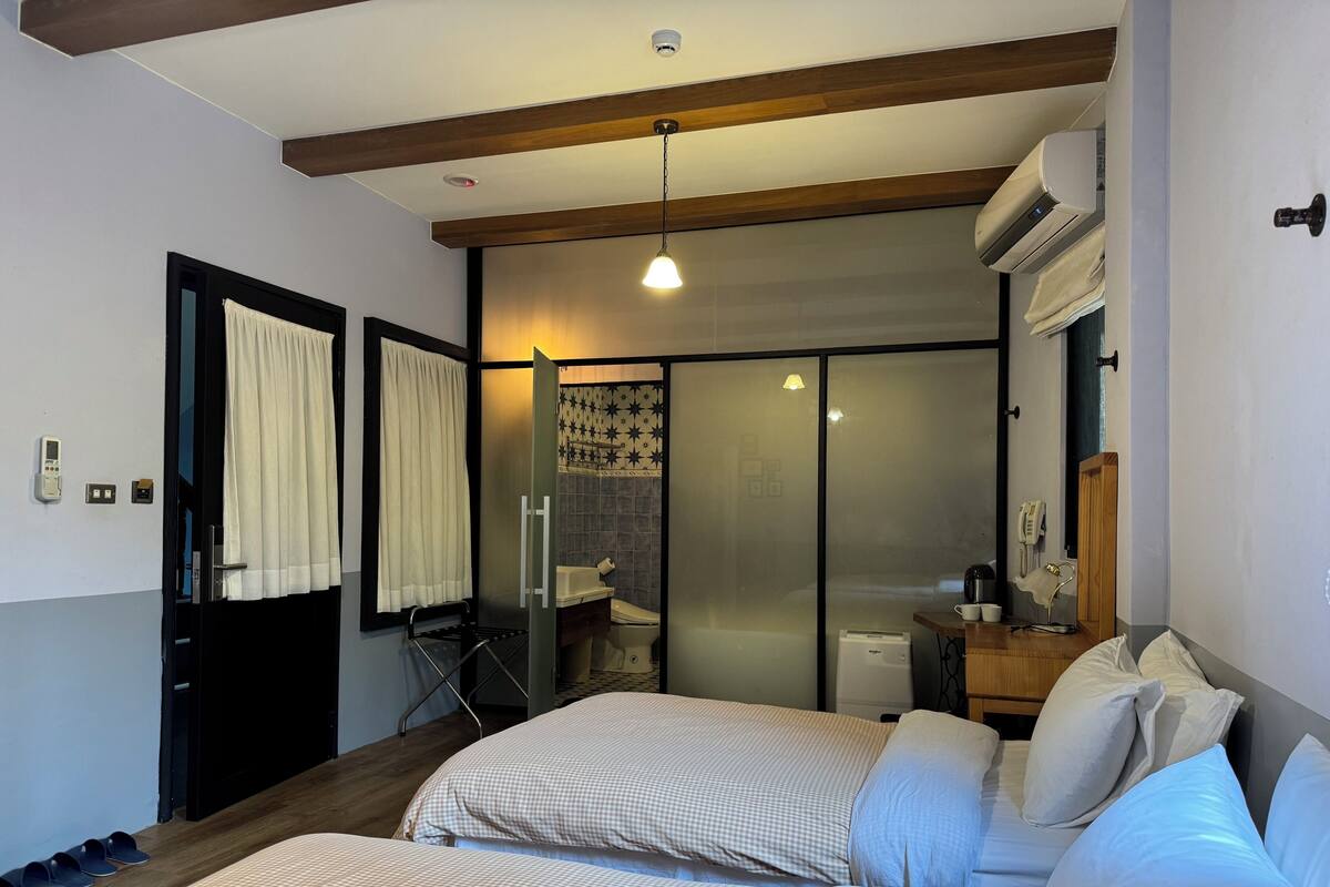 A bedroom with a bed, a bedside table, a mirror, and a sliding door leading to a bathroom.