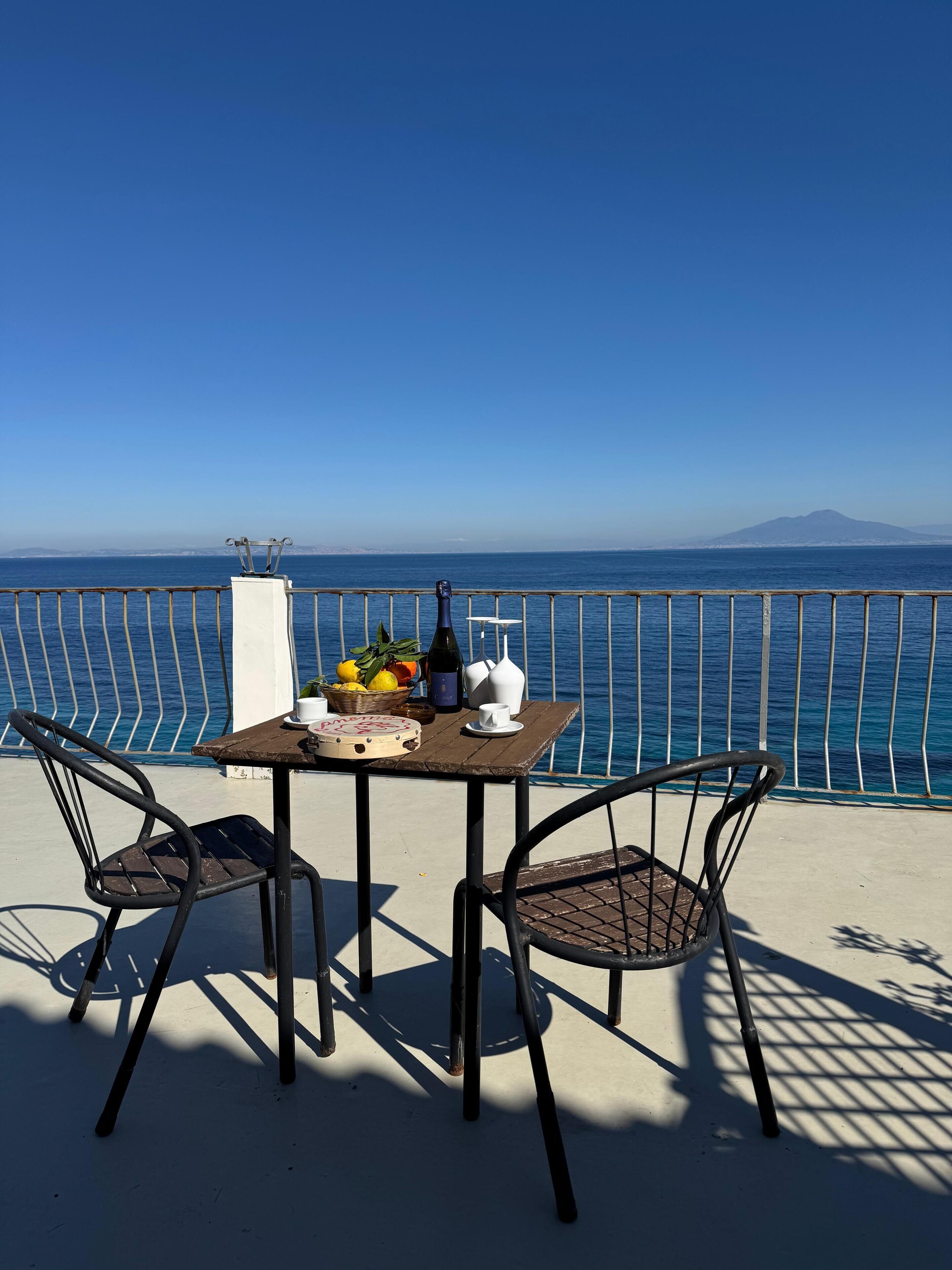A table with chairs and a view of the sea.