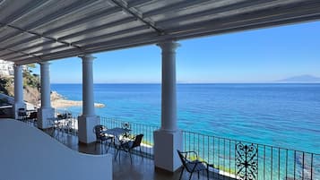 Una terraza con vista al mar, que ofrece asientos al aire libre y una barandilla.