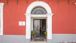 Fachada de hotel roja, con columnas blancas y puerta de cristal.