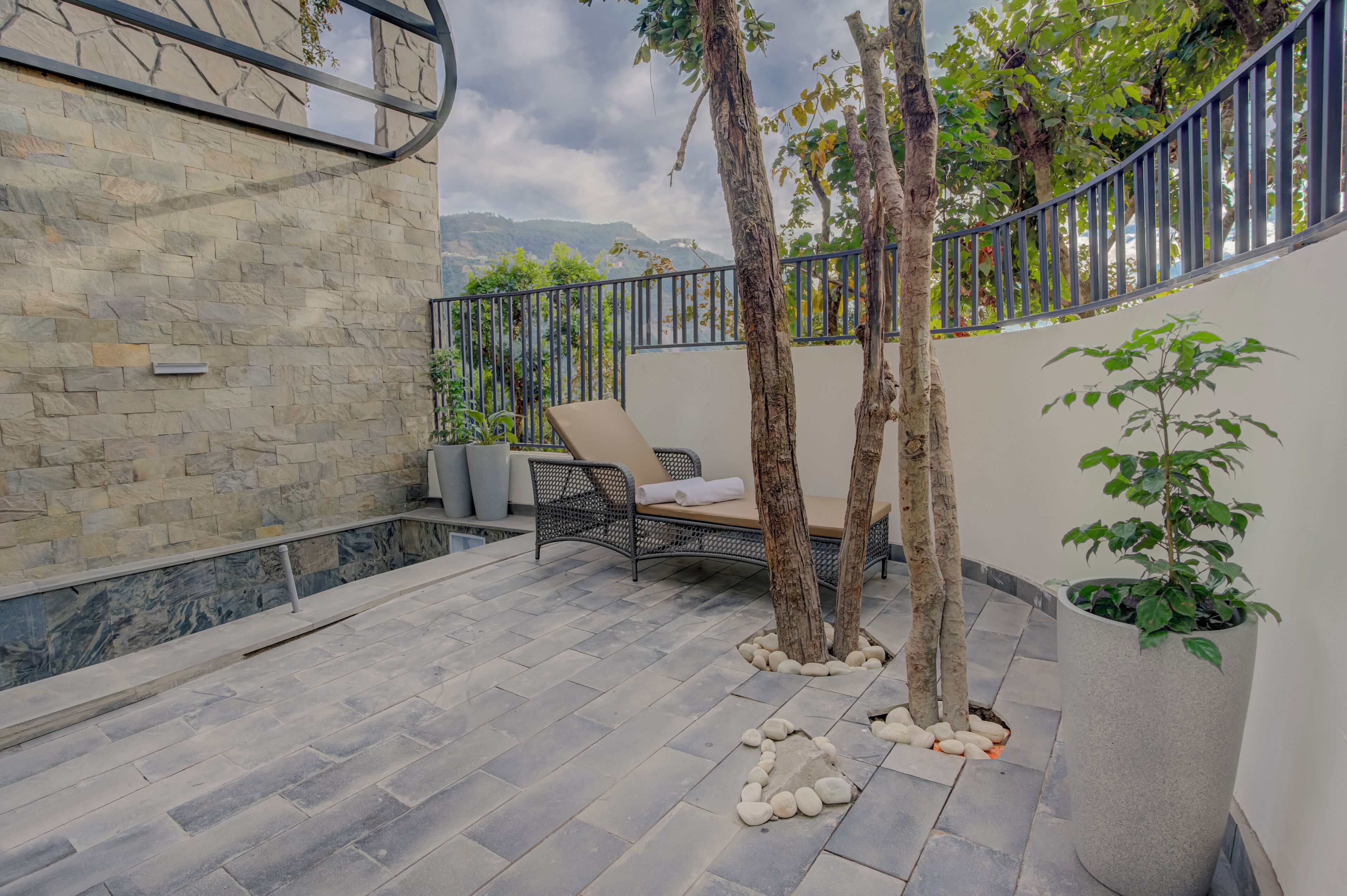 A stone-walled patio with a lounge chair, a small table, and a potted plant.