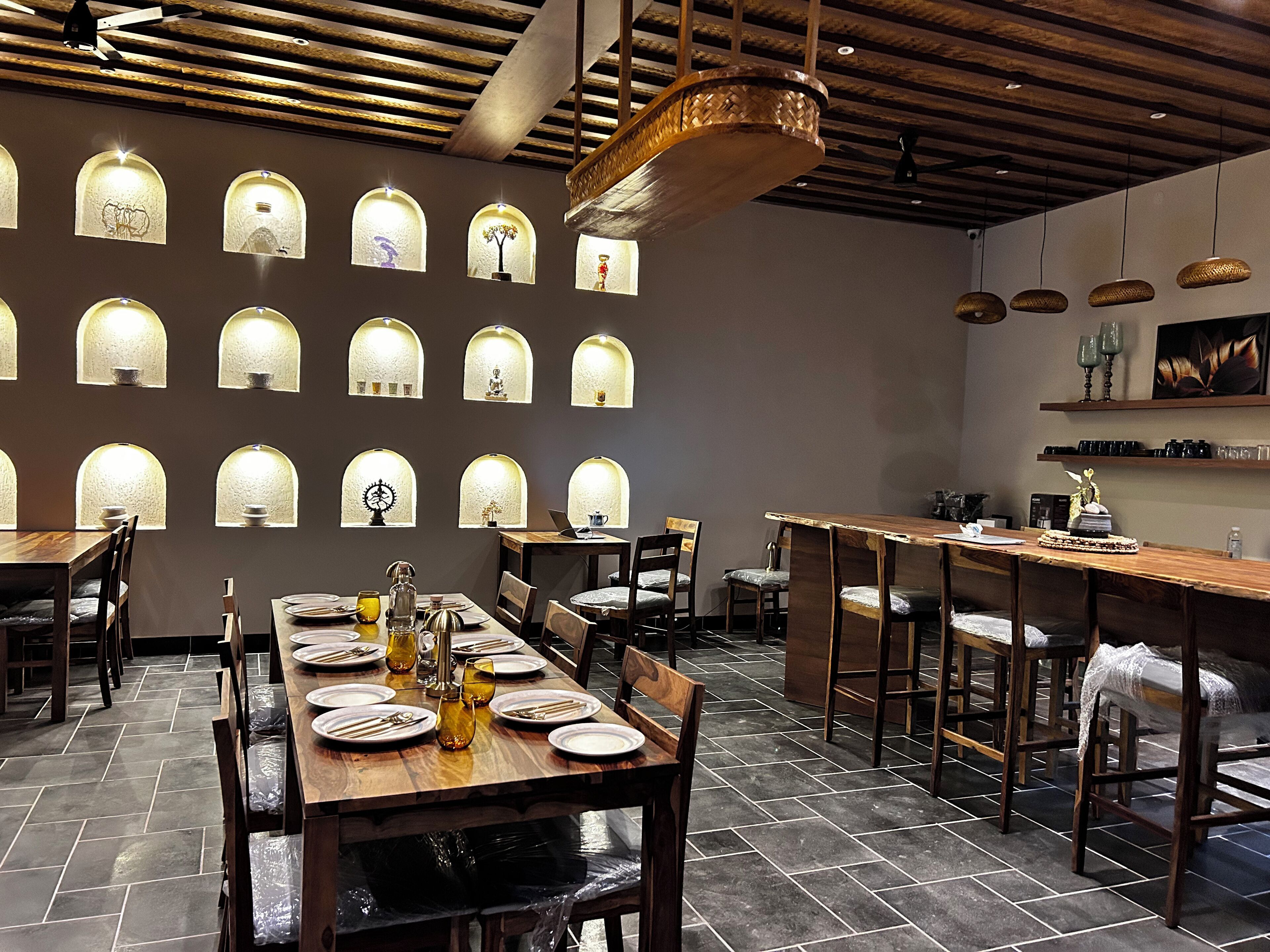 Un interno ristorante con diversi tavoli, sedie e vari lampadari a parete.