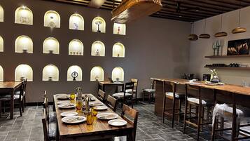 Un interno ristorante con diversi tavoli, sedie e vari lampadari a parete.