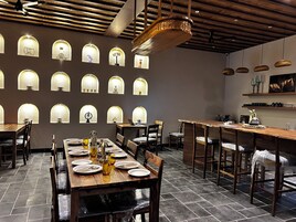 Un interno ristorante con diversi tavoli, sedie e vari lampadari a parete.
