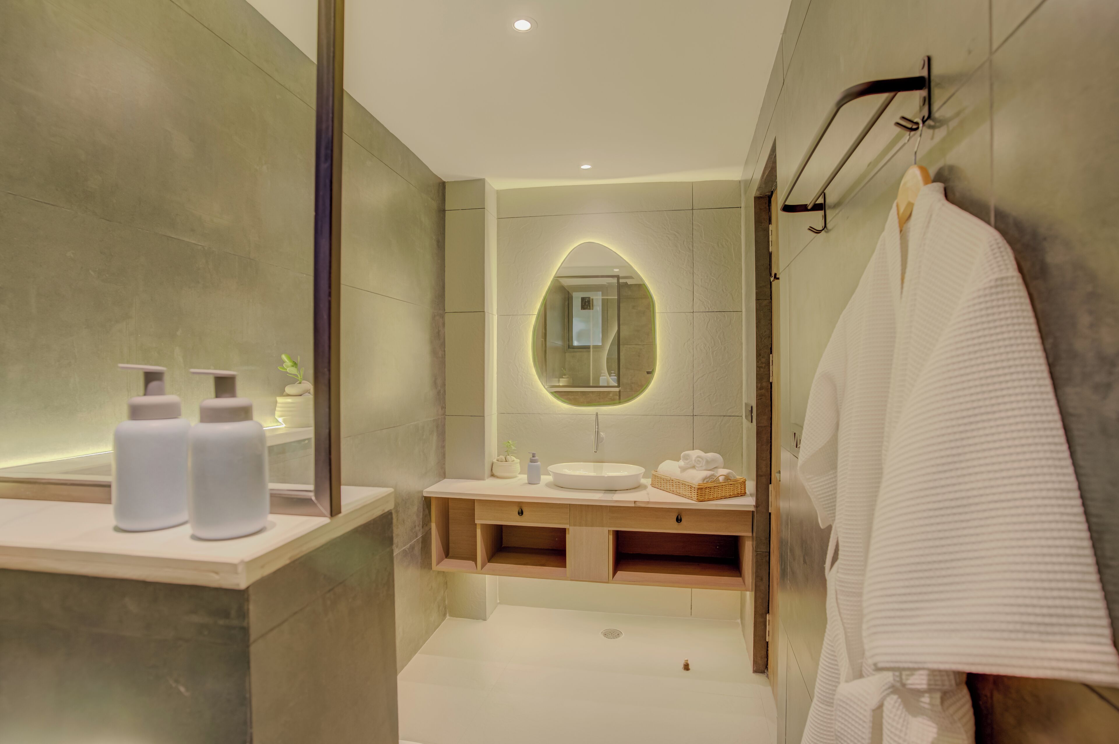 Un baño moderno con un espejo grande, un lavamanos y un perchero para toallas.