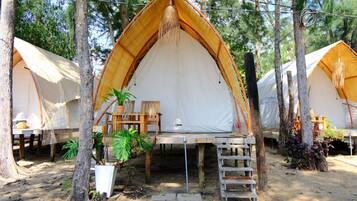A series of dome-shaped tents with wooden benches and tables, surrounded by trees.