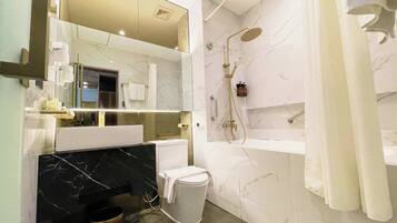 A modern bathroom with a marble vanity, a toilet, a shower with a handheld showerhead, and a towel rack.