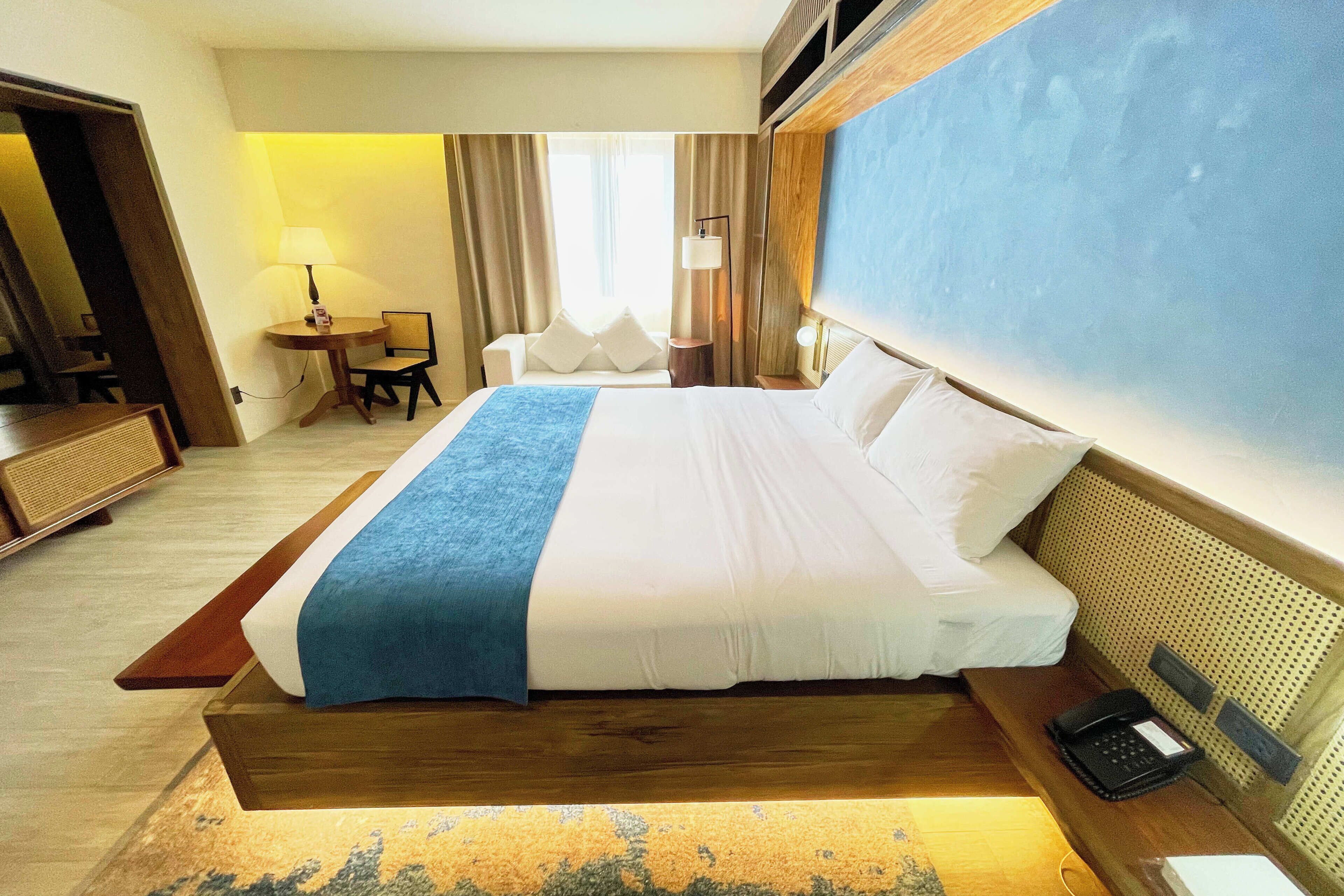 Une chambre d’hôtel avec un grand lit, des tables de chevet, un bureau et une chaise.